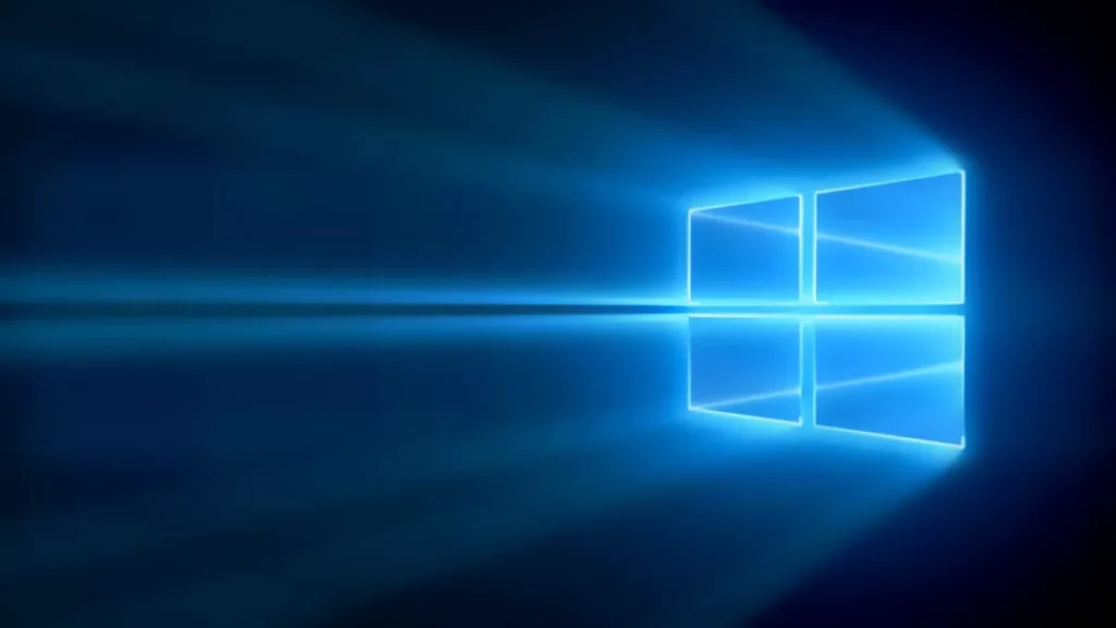 Glowing blue Windows logo against a dark background, with light beams extending from the logo. Reflective effect creates a symmetrical, futuristic look.