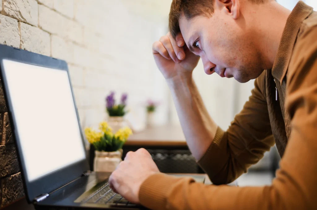 Frustrated user staring at an unresponsive laptop, illustrating a laptop system crash or computer freezing problem.