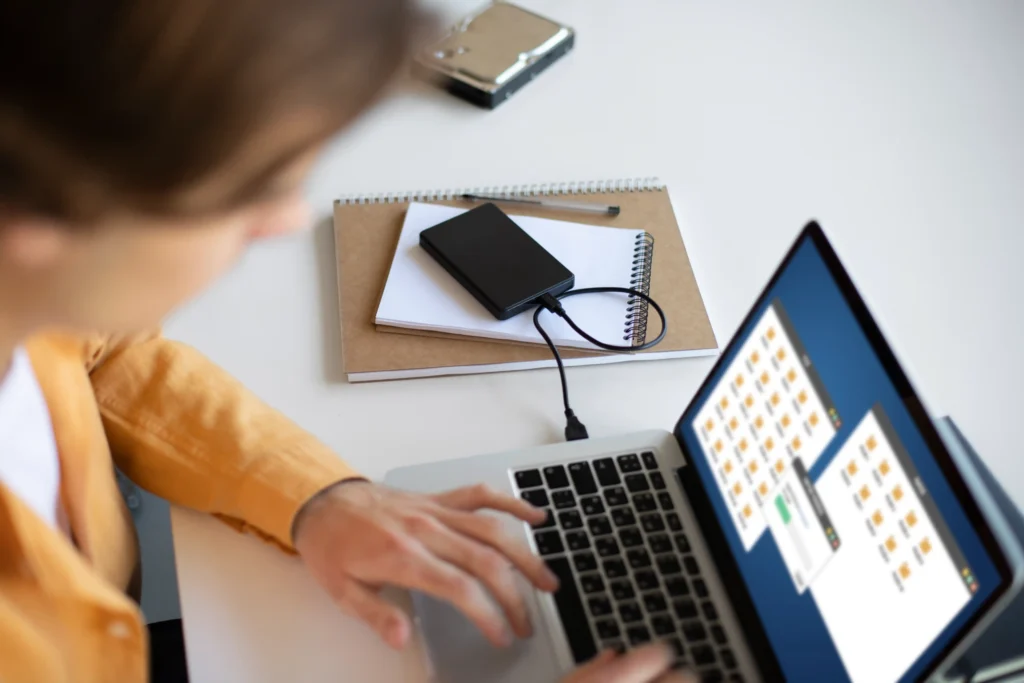 External USB drive connected to a laptop while a user works, representing the process of setting up ReadyBoost.