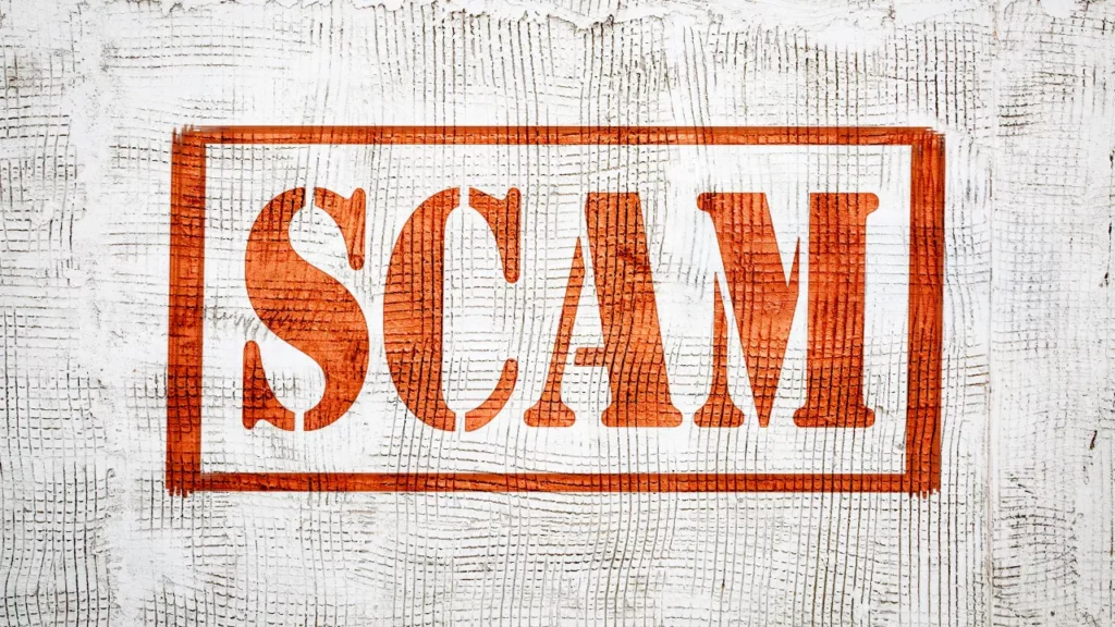 The image shows the word "SCAM" in bold, red letters inside a red rectangle on a textured white background, conveying a warning or cautionary tone.