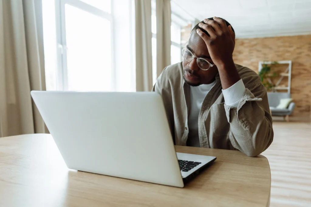 A frustrated person looking at a laptop while resting their hand on their head, suggesting concern about a computer restart problem.