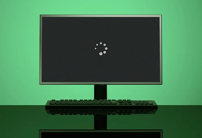 Windows startup black screen with loading animation on a desktop monitor.