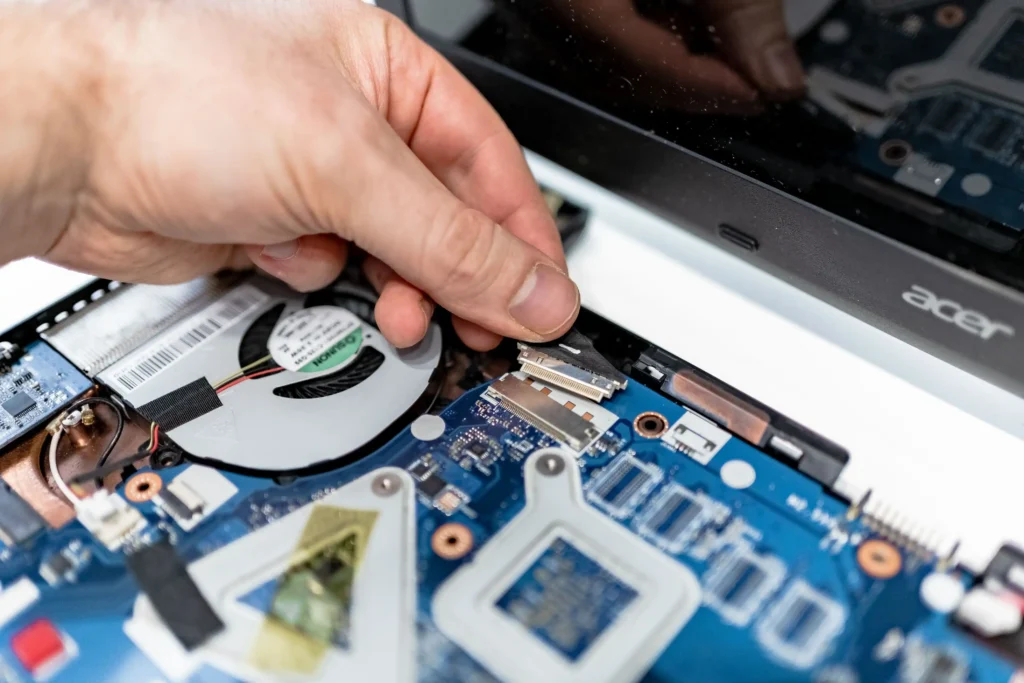 Technician inspecting and repairing internal laptop components and connectors.