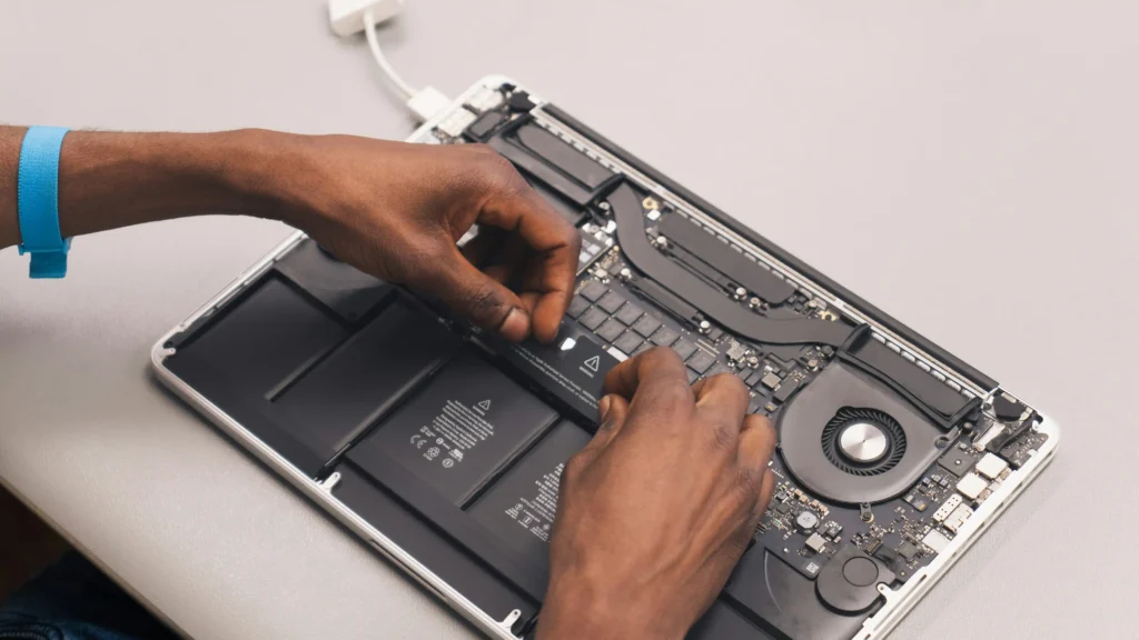 Technician replacing the battery inside a MacBook during a battery replacement service