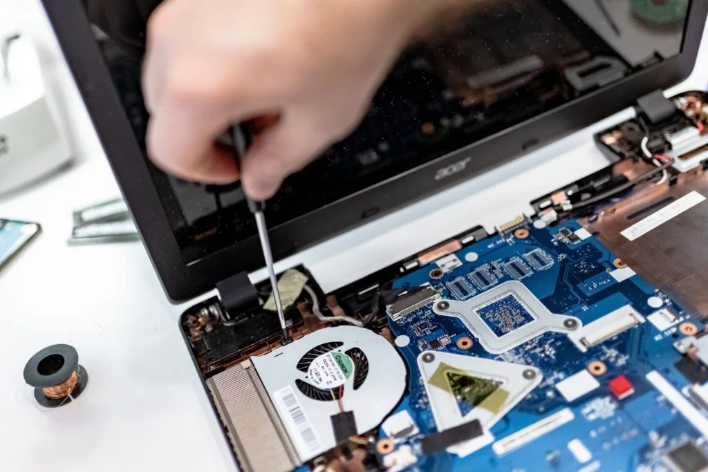 Technician inspecting the internal components of an open laptop with a screwdriver during professional laptop repair.