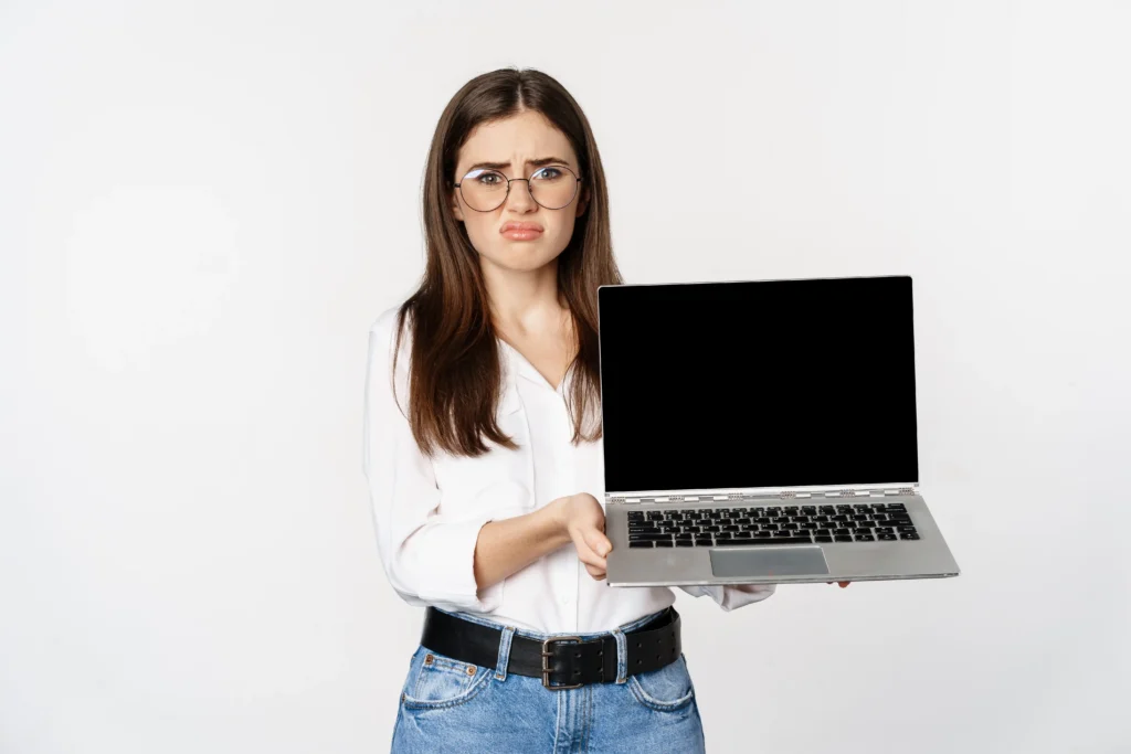 Woman looking concerned while holding a laptop with a completely black display.